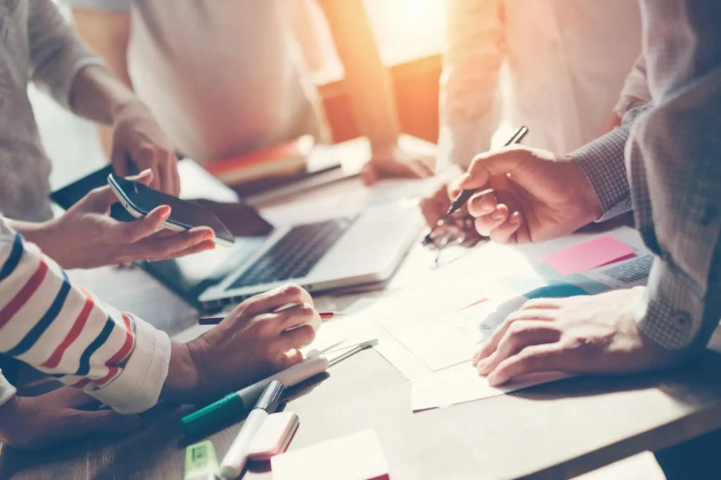 Mains échangeant et annotant des feuilles posées sur un bureau
